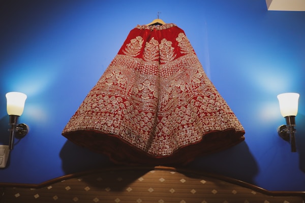 A vibrant traditional dress with colorful embroidery hanging on a wooden hanger.