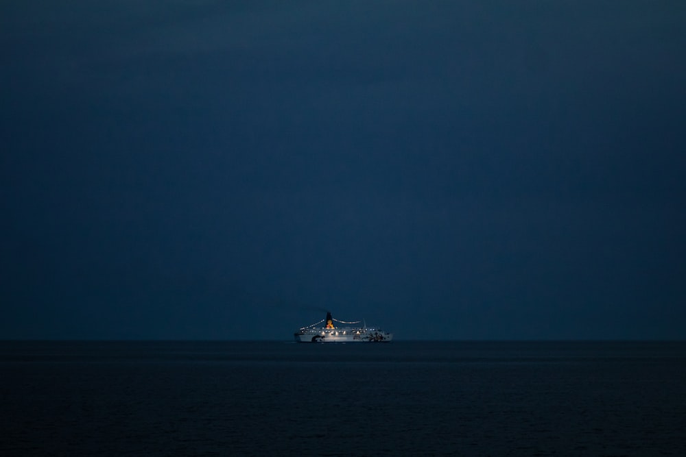 white ship on sea under gray sky