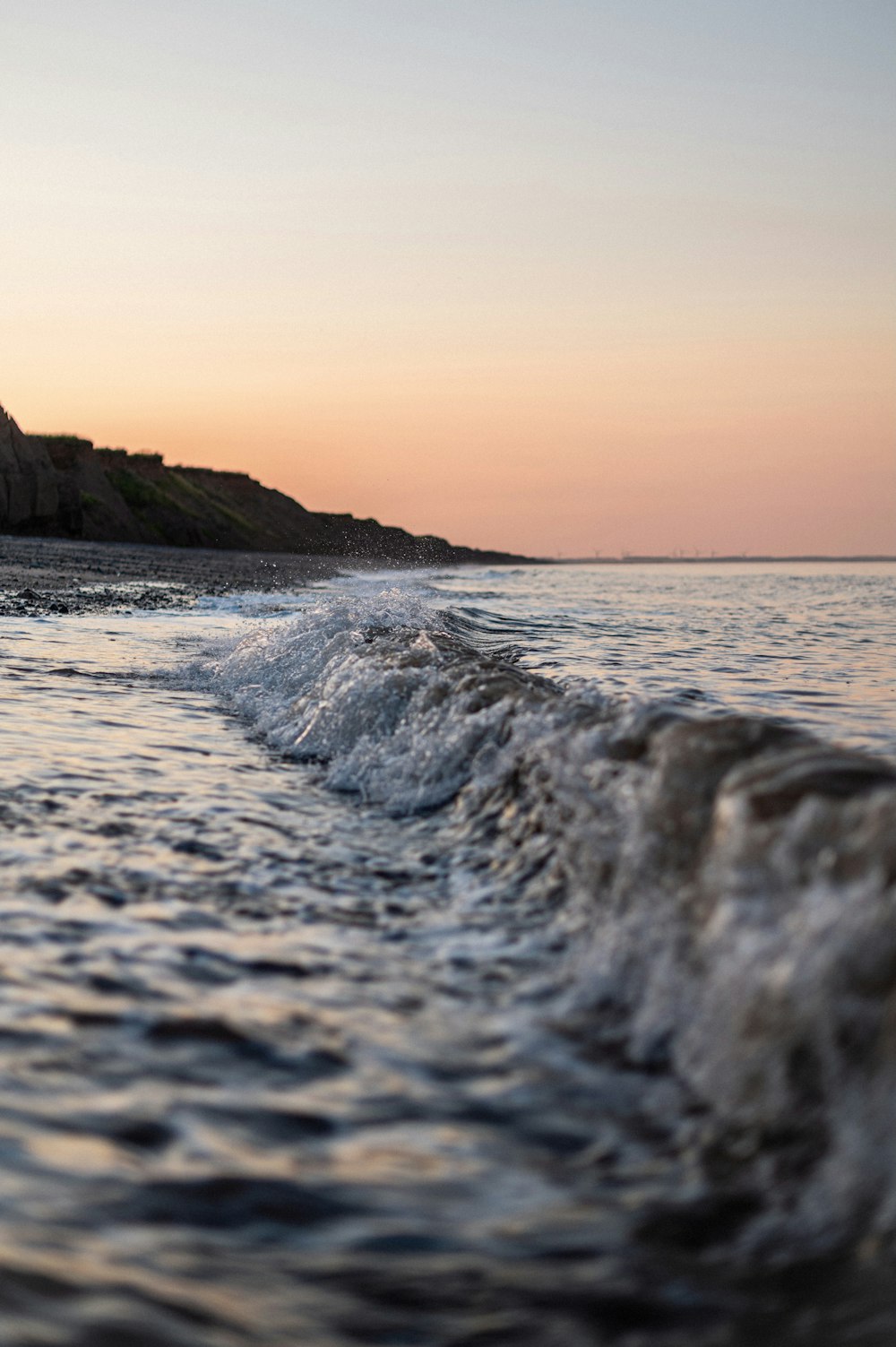 ocean waves crashing on shore during sunset