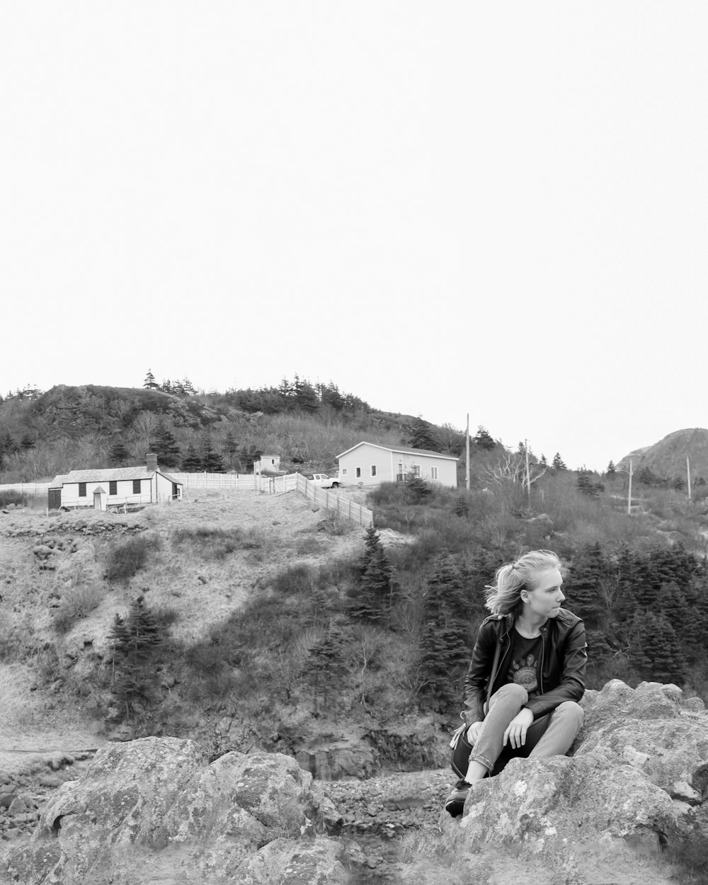 grayscale photo of woman sitting on rock