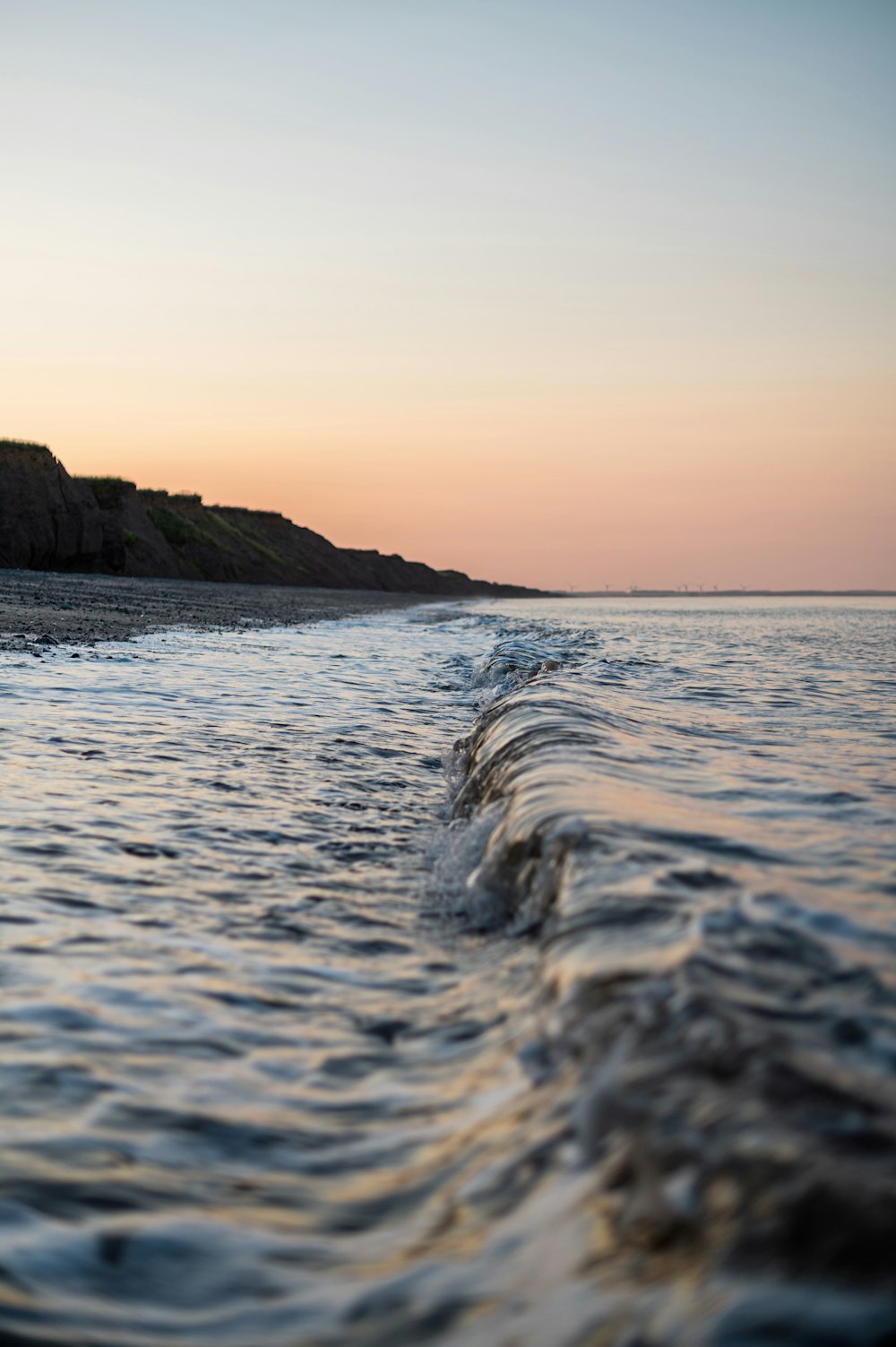 ocean waves crashing on shore during sunset