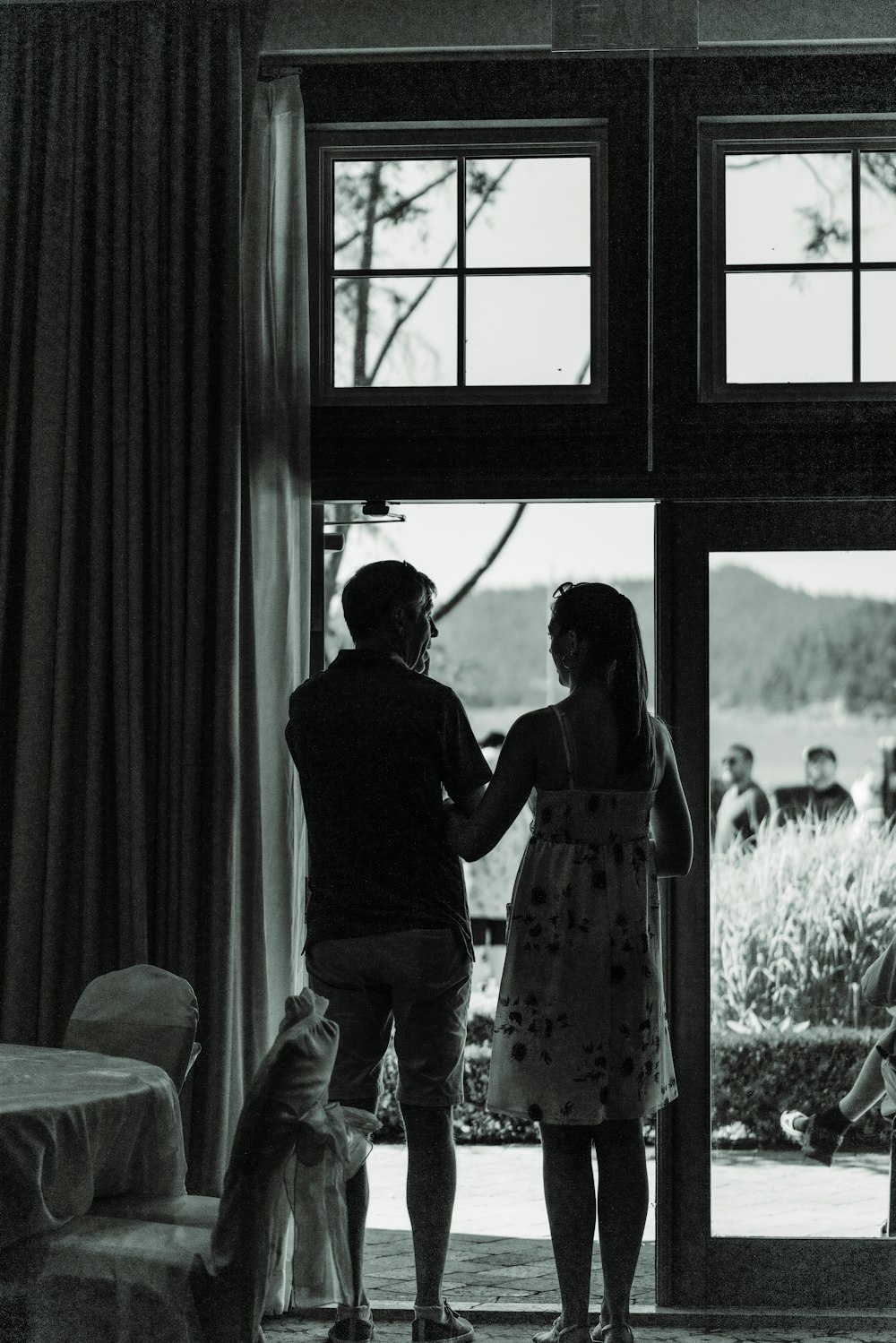 man and woman kissing in front of window