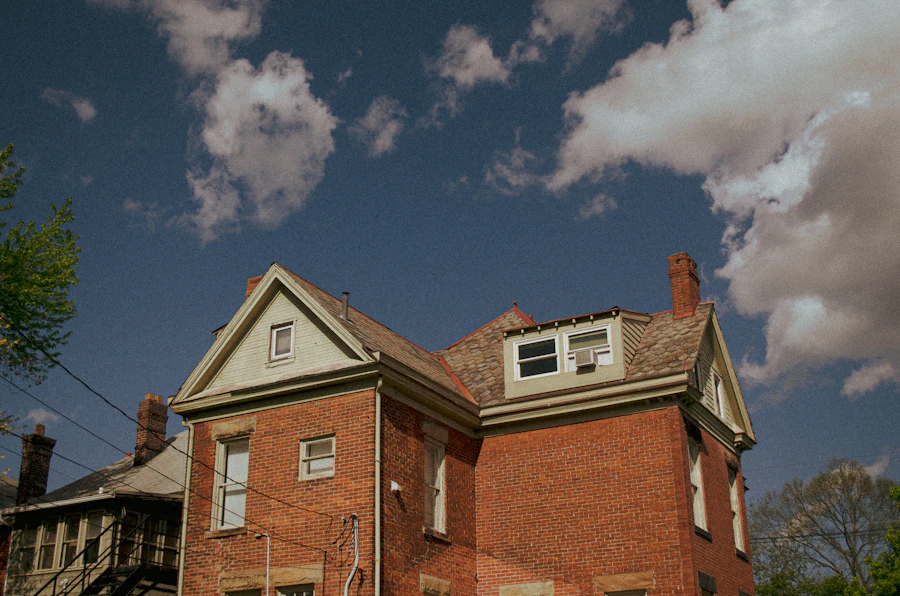 A brick house with a gabled roof under clouds