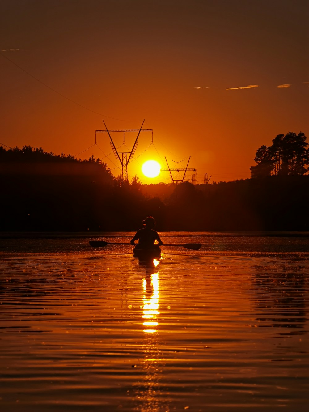 Silueta de la persona que monta a caballo en el agua durante la puesta del sol