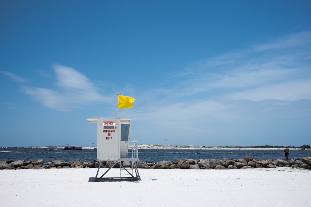 Torre di salvataggio bianca e blu sulla riva della spiaggia durante il giorno