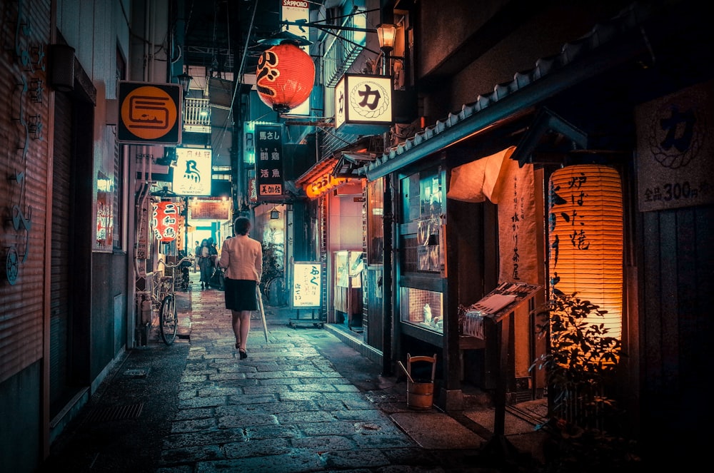 woman in black jacket walking on sidewalk during night time