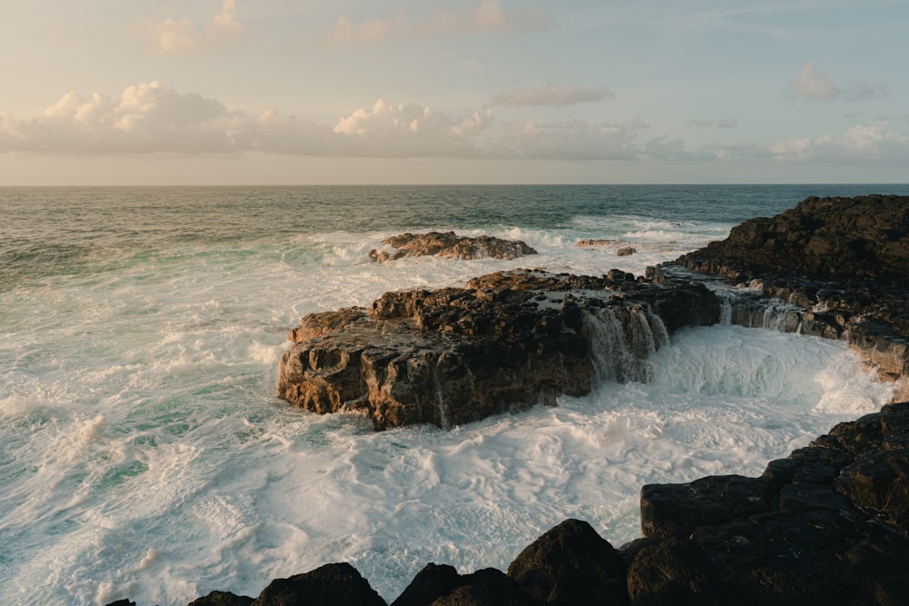 brown rock formation on sea under white clouds during daytime