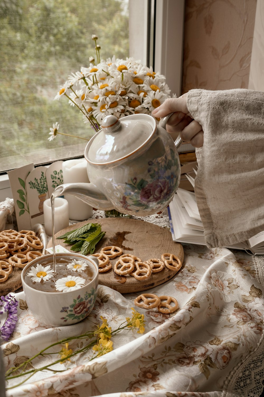 person holding white ceramic teapot pouring white liquid on white ceramic teacup