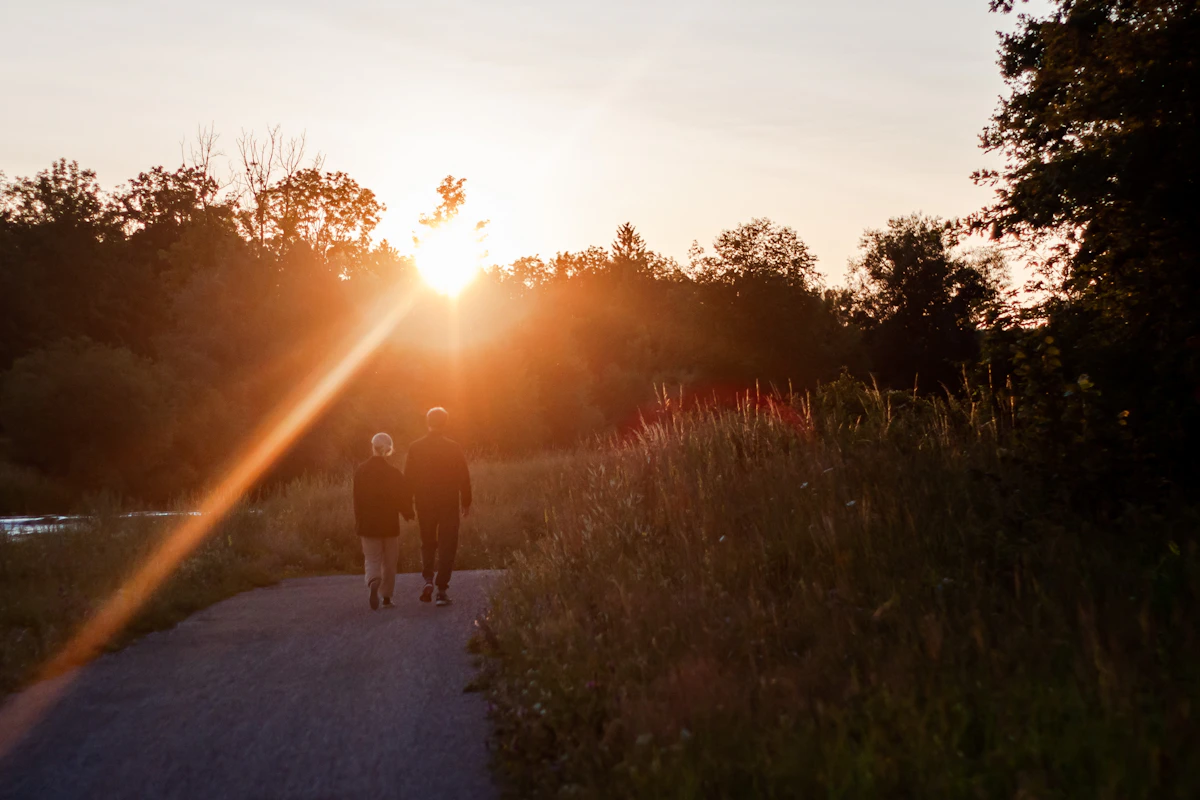 Two people walking a quiet path toward the evening sun