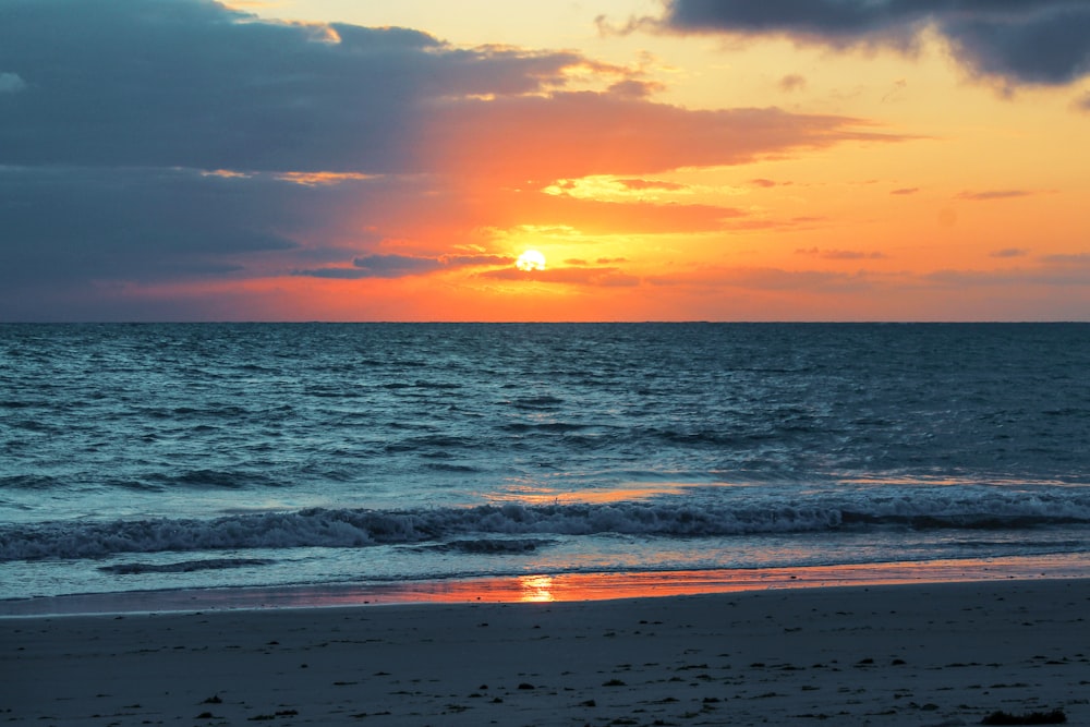 sea waves crashing on shore during sunset