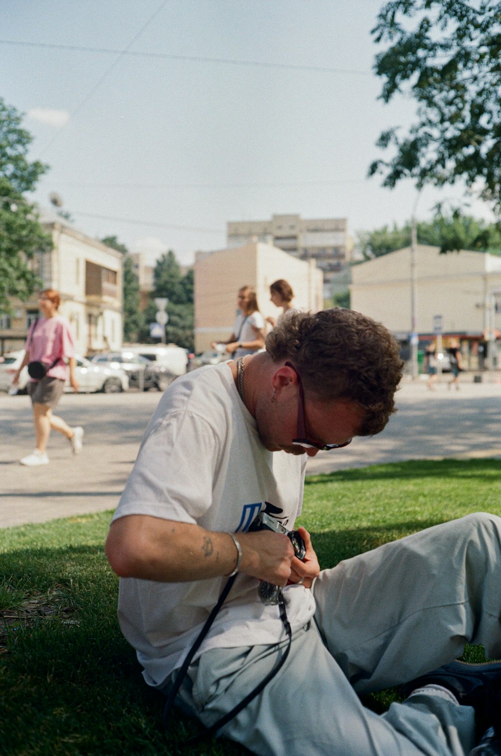 man in white t-shirt and black sunglasses sitting on green grass field during daytime