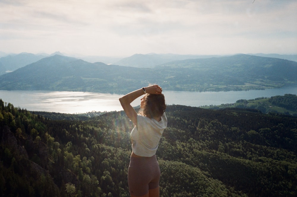 woman in white shirt standing on top of mountain during daytime