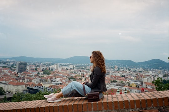woman in blue denim jacket sitting on brown roof top during daytime in Kunsthaus Graz Austria