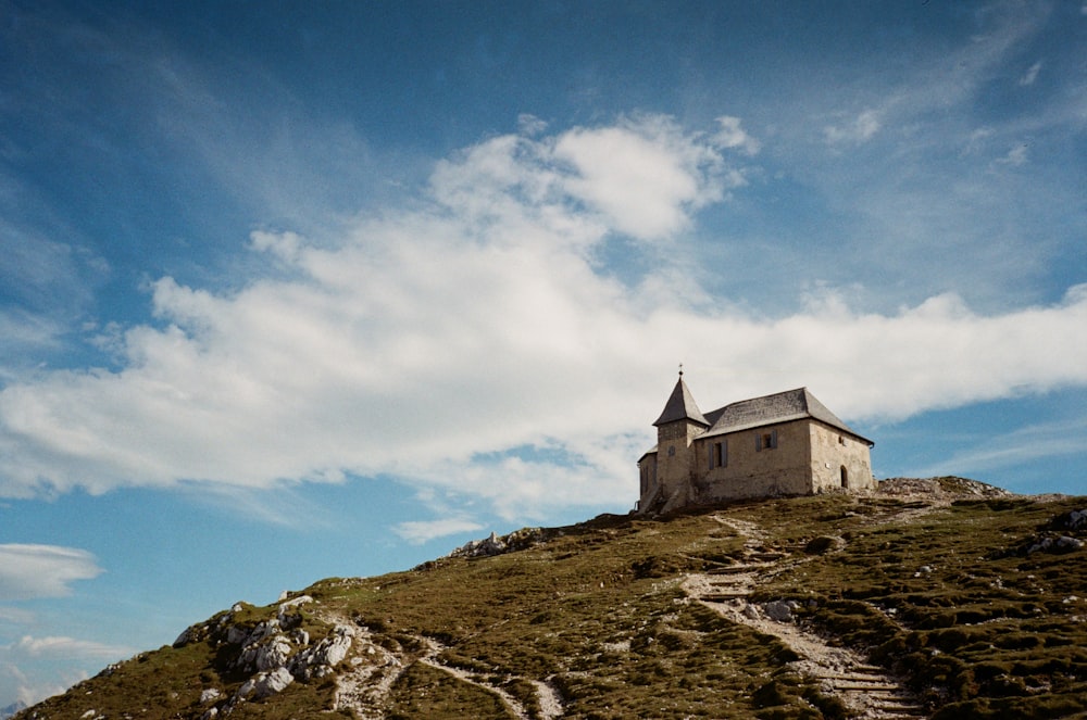 white and gray concrete building on top of hill under blue sky and white clouds during