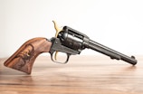 Close-up of a classic revolver resting on a wooden table.