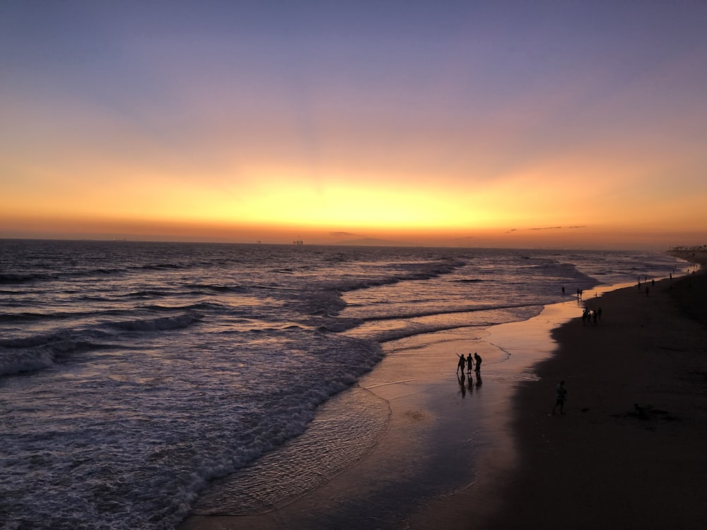 people walking on beach during sunset