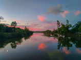 A sunset view over a sparkling, trash-free river winding through green trees.