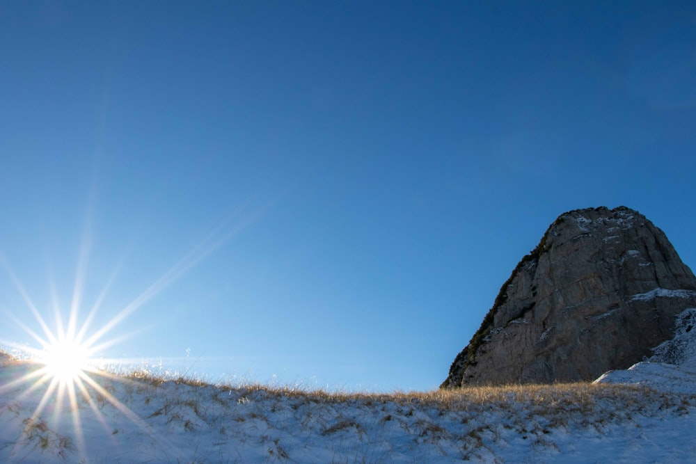 Formación rocosa marrón en campo de nieve blanca bajo cielo azul durante el día