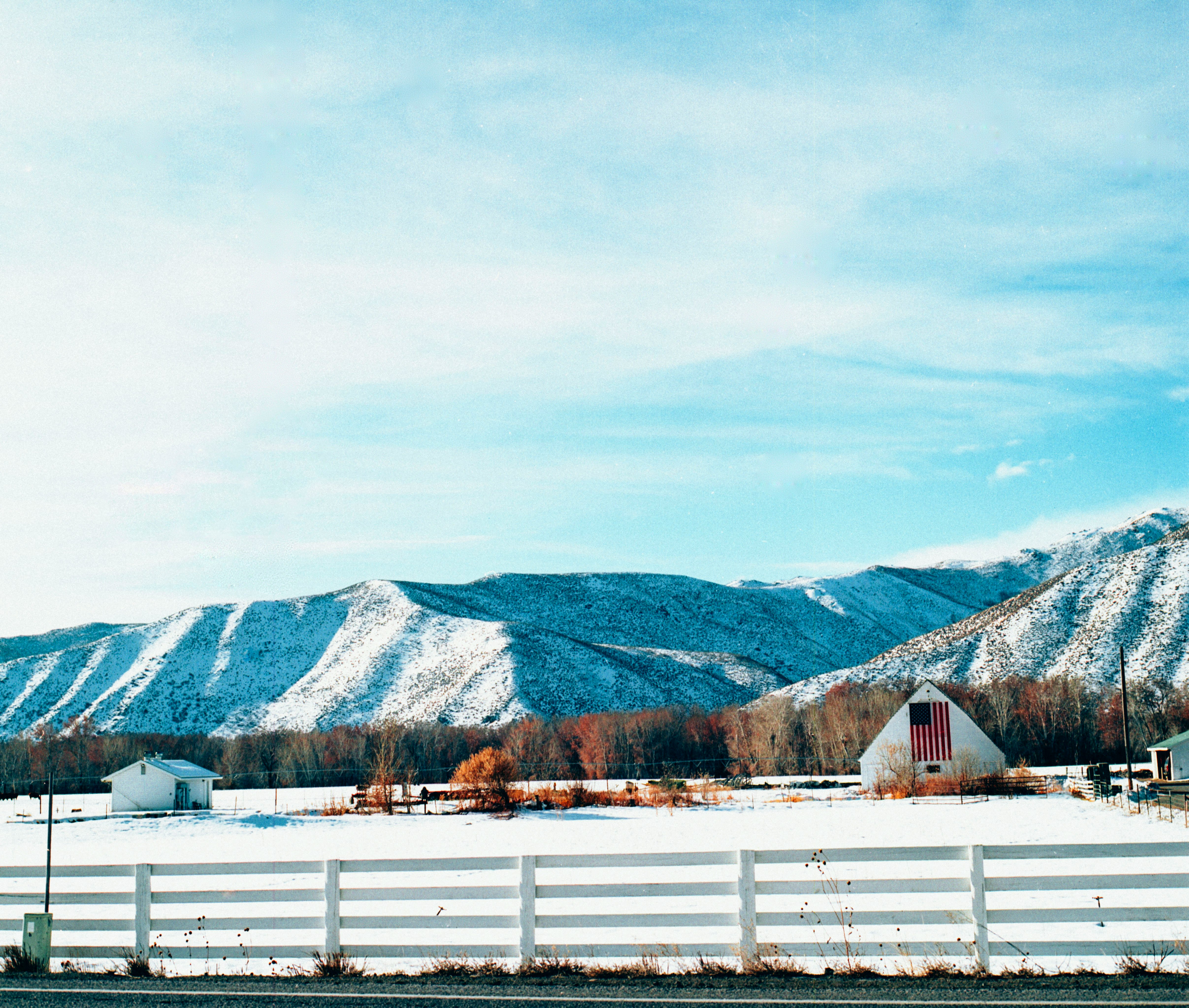 white wooden fence near mountain under white sky during daytime