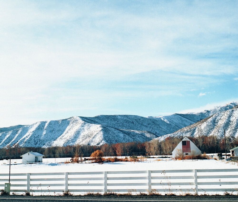 white wooden fence near mountain under white sky during daytime