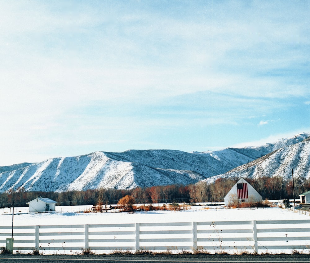 valla de madera blanca cerca de la montaña bajo el cielo blanco durante el día