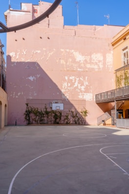 An outdoor basketball court surrounded by modern city buildings, showcasing clean lines and bright markings.
