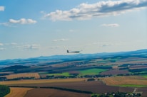 A glider soaring gracefully above a green landscape during launch.