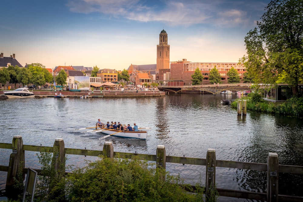 weißes und blaues Boot tagsüber auf dem Wasser in der Nähe von braunem Betongebäude