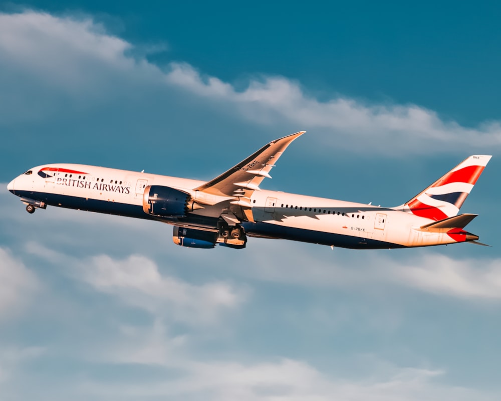 weiß-rotes Flugzeug tagsüber in der Luft unter blauem Himmel