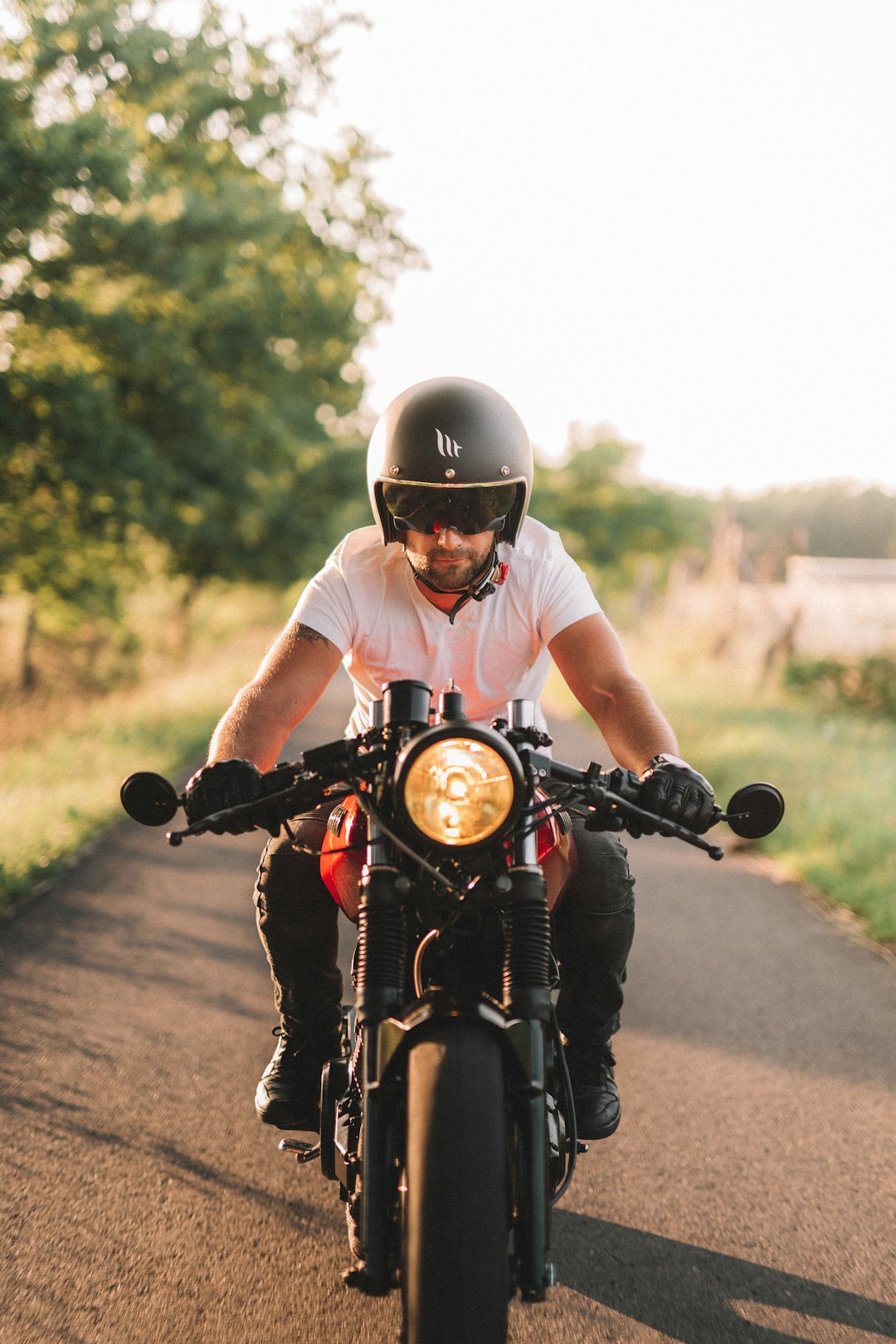 man in white shirt riding motorcycle on road during daytime