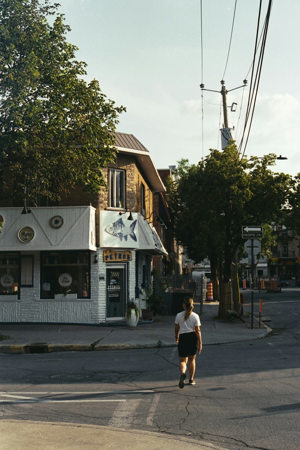 woman in white t-shirt walking on sidewalk near building during daytime