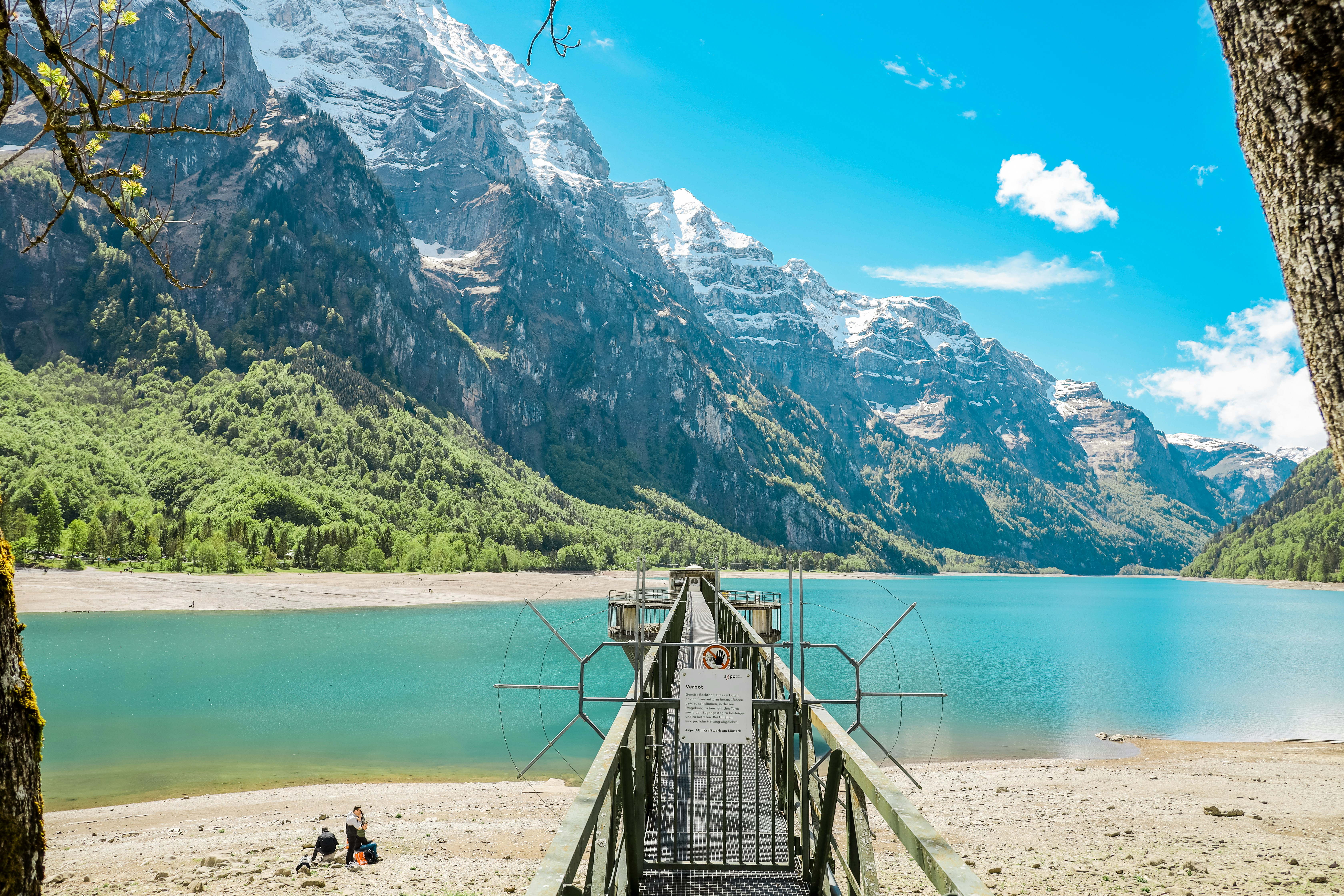 brown wooden bridge on lake near mountain range