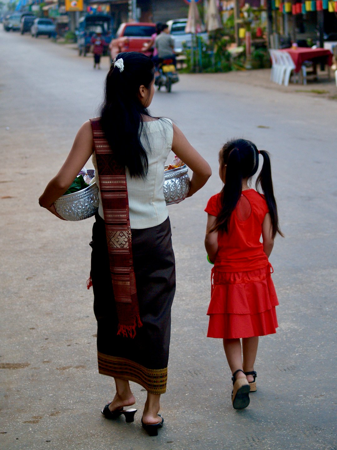 2 women in red dress standing on gray asphalt road during daytime