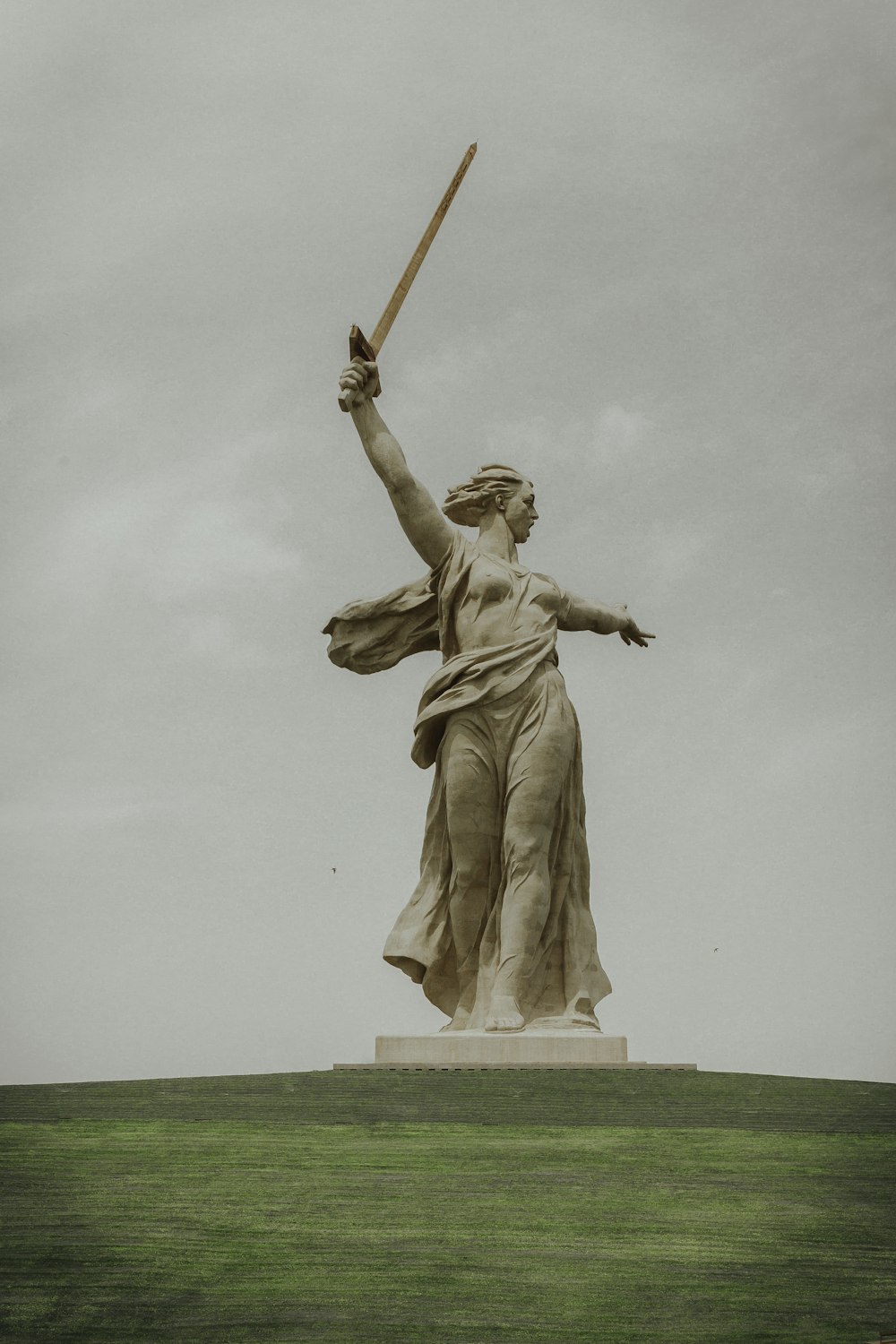 man holding stick statue during daytime