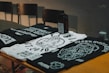 Flat lay of black, red, and white streetwear t-shirts on a wooden surface