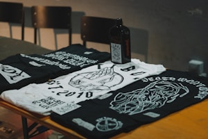 Flat lay of three rock band t-shirts in black, gray, and white with striking graphic designs