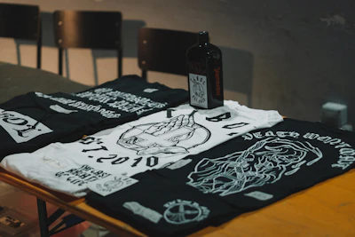 Close-up of trendy t-shirts with bold prints displayed on a rustic wooden table.