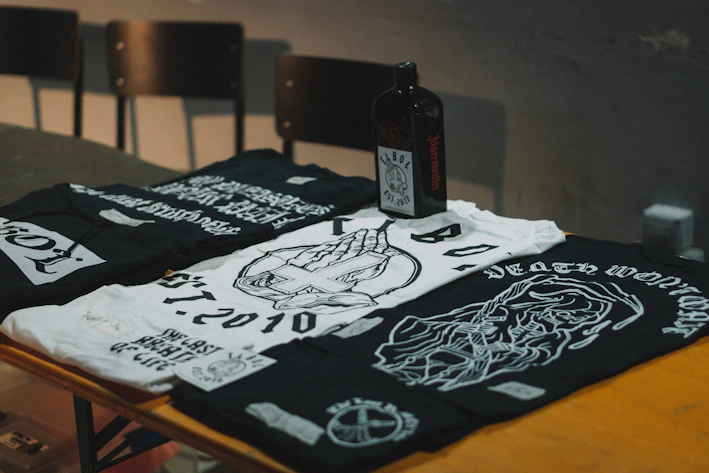 A cozy flat lay of neutral-toned geek-themed t-shirts with subtle anime and gaming prints.