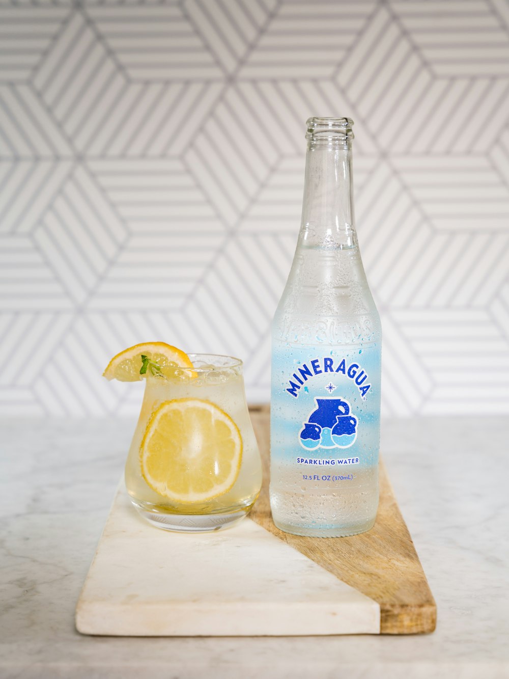 clear glass bottle beside clear drinking glass with lemon juice