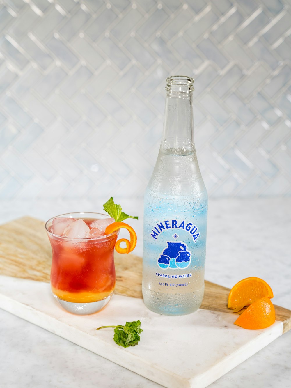 blue labeled bottle beside clear drinking glass