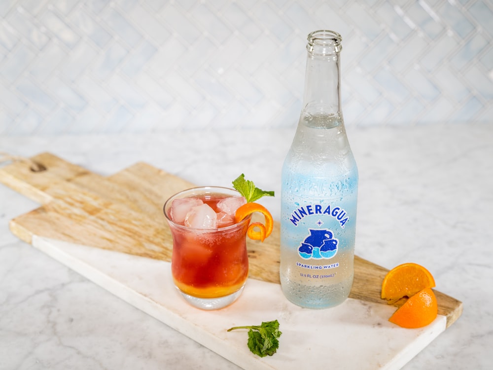 blue labeled bottle beside clear drinking glass with red liquid