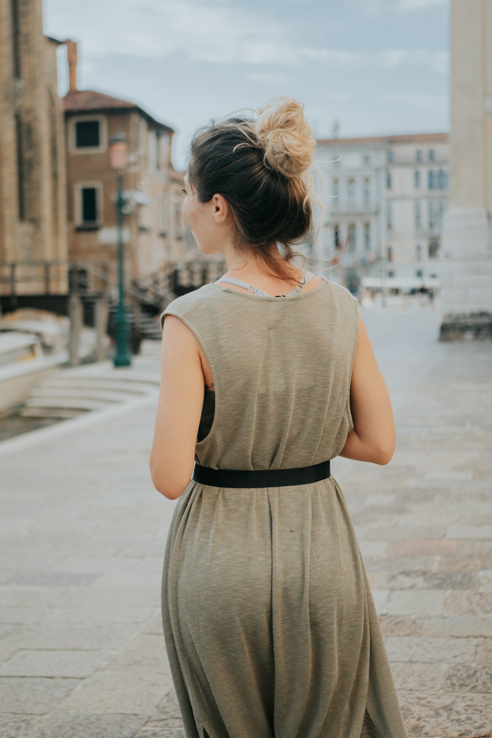 woman in gray sleeveless dress standing on sidewalk during daytime