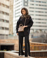A stylish woman in a sleek blazer and trousers, confidently posing against a modern urban backdrop.