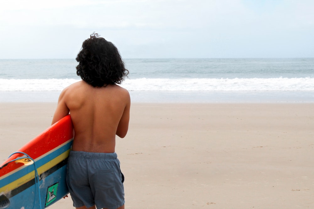 topless boy in black shorts standing on beach during daytime