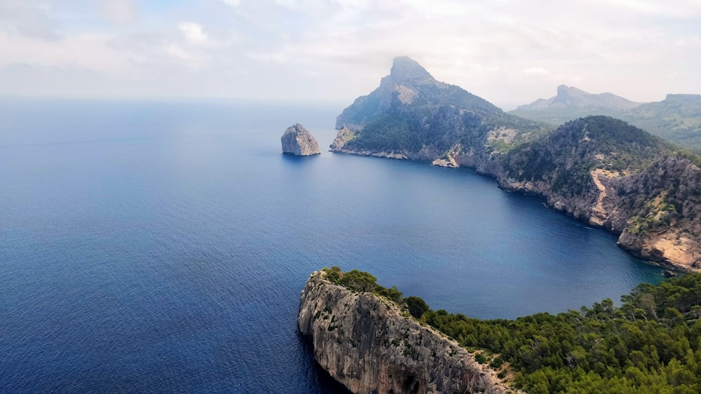 green and brown mountain beside blue sea under white sky during daytime