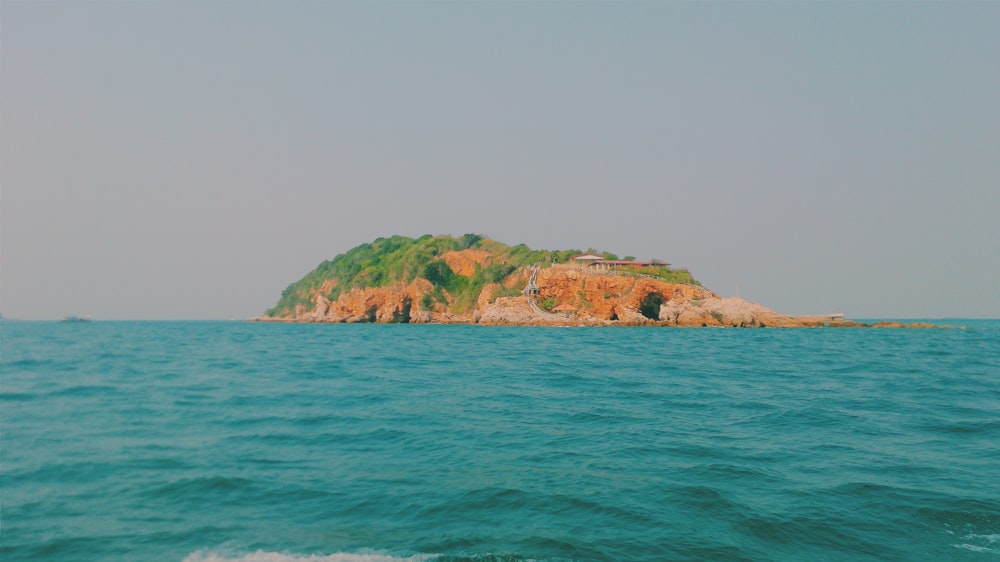 Braune und grüne Insel auf blauem Meer unter weißem Himmel tagsüber