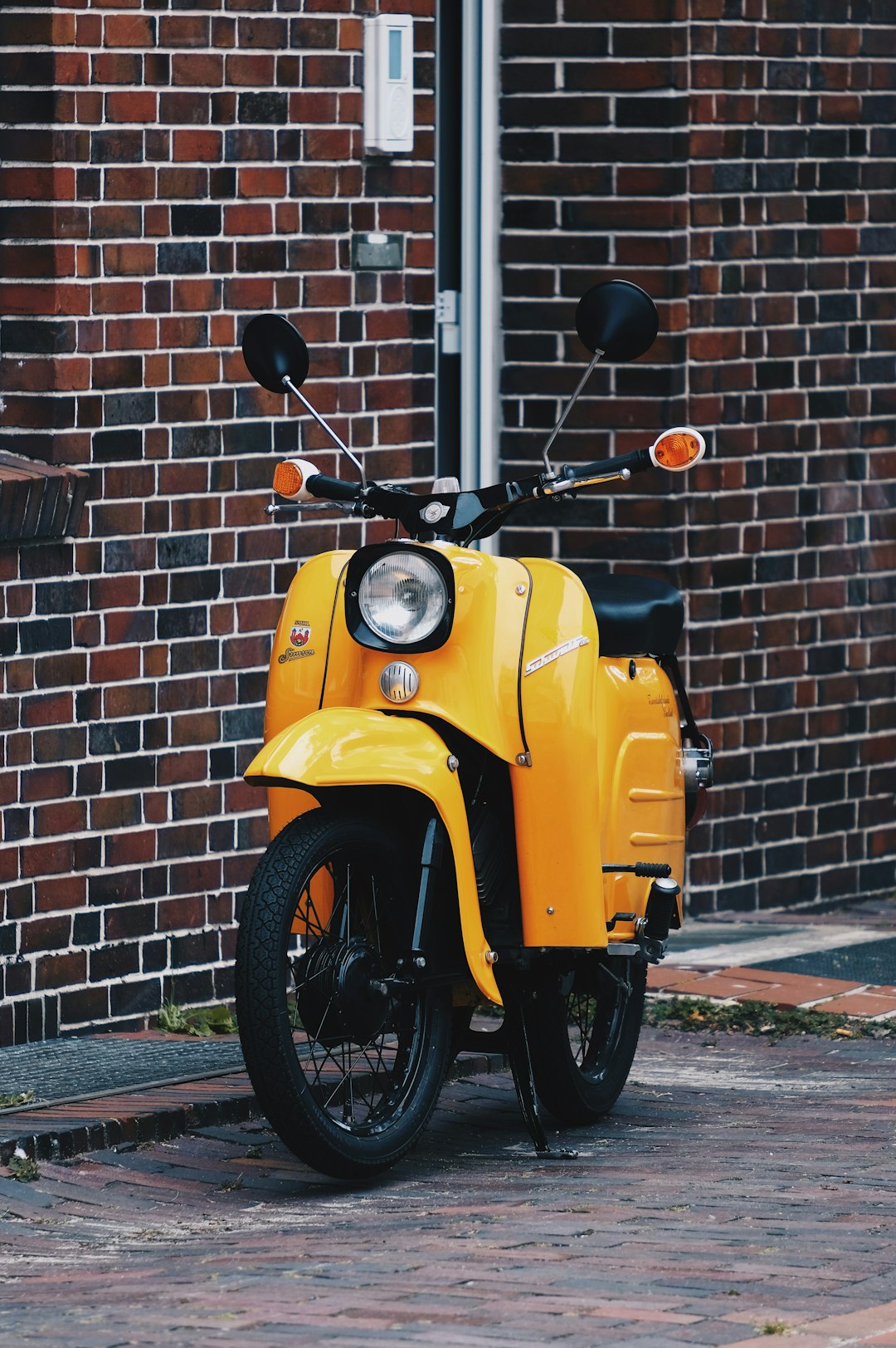yellow and black motorcycle parked beside brown brick wall