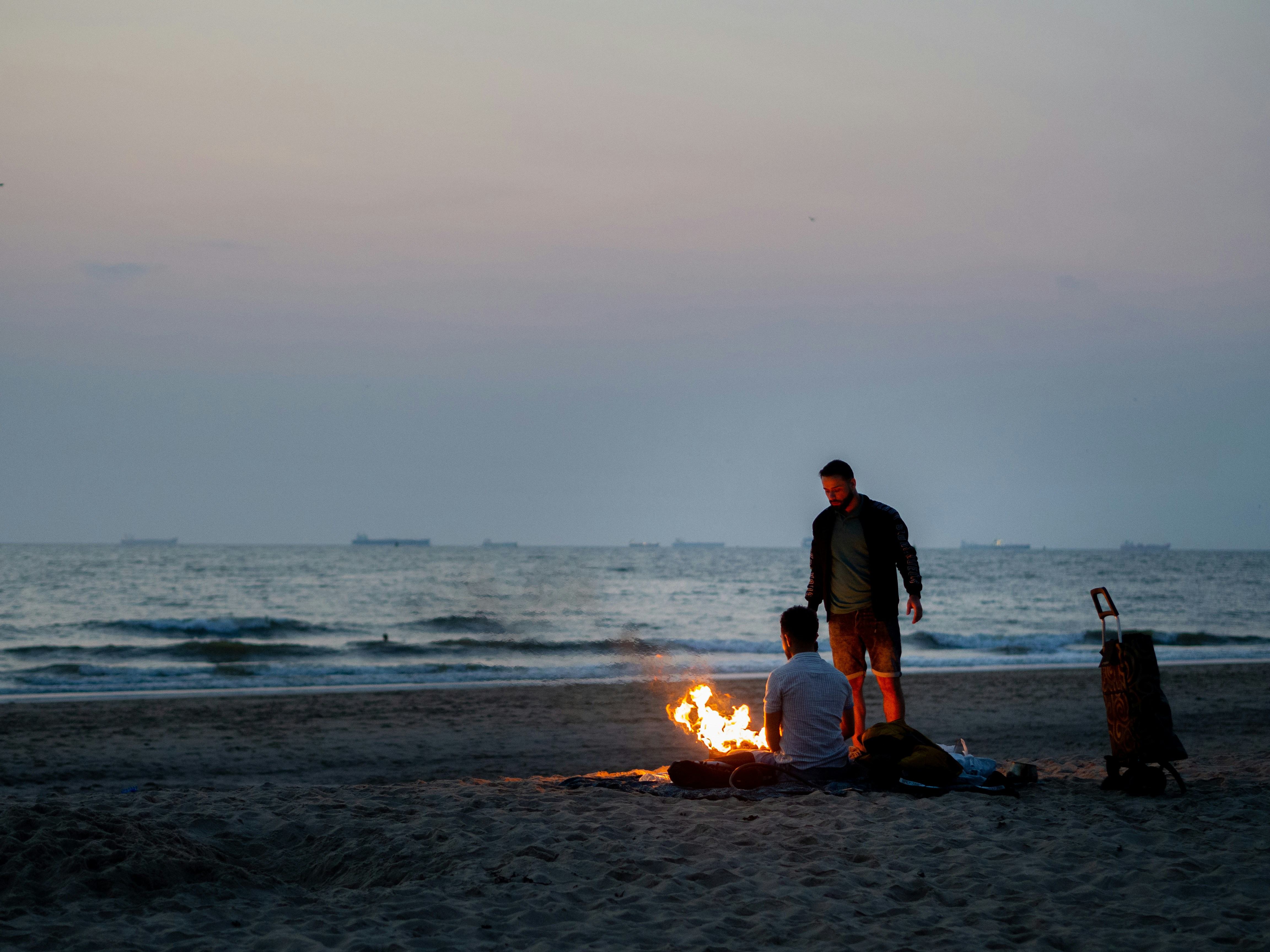 homme et femme assis sur le rivage de la plage au coucher du soleil