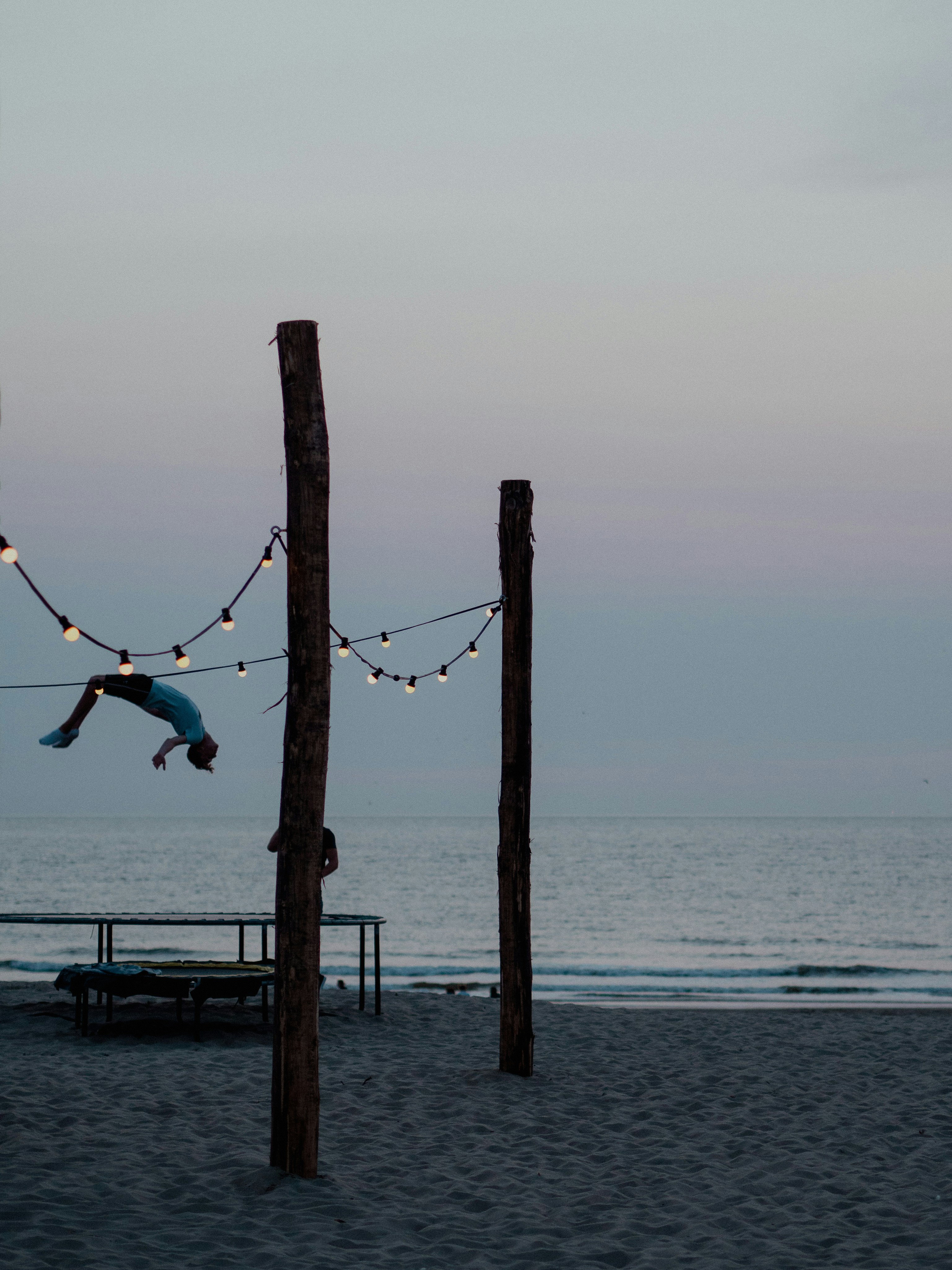 personne en chemise blanche et pantalon noir assis sur le quai en bois brun pendant la journée