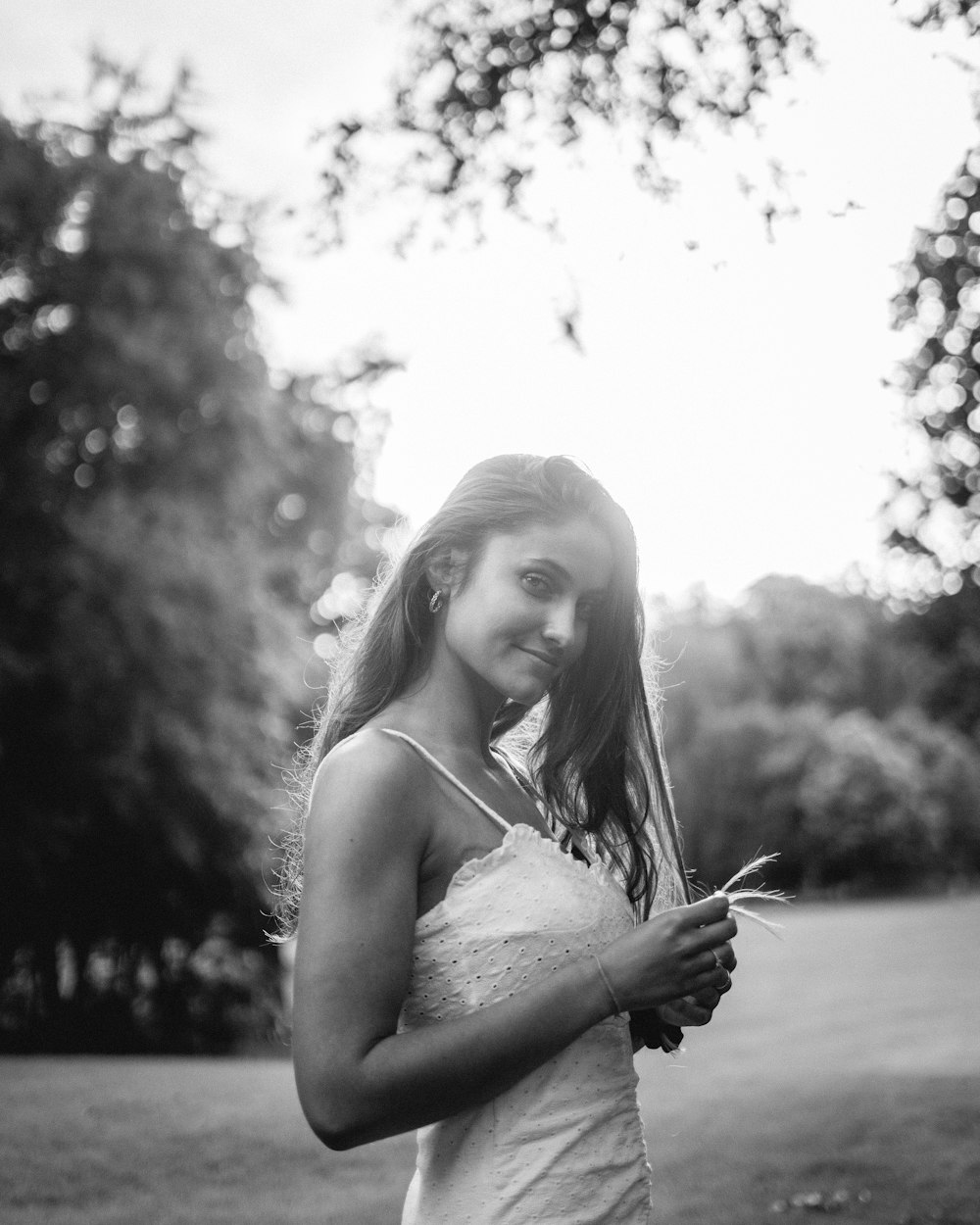 grayscale photo of woman in tank top holding her hair